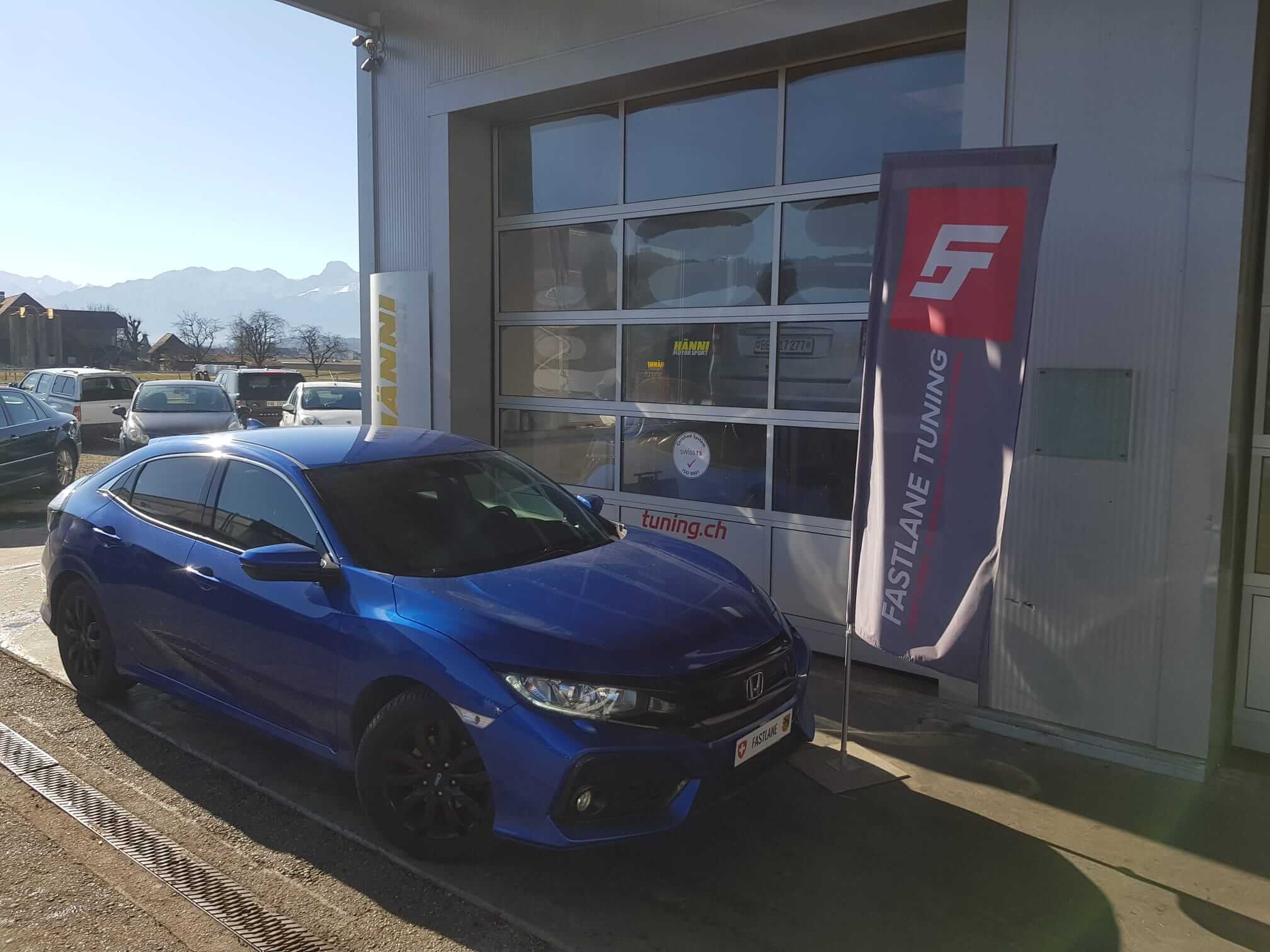 Ein blauer Honda Civic der 10. Generation steht neben der Fastlane Tuning Schweiz Flagge