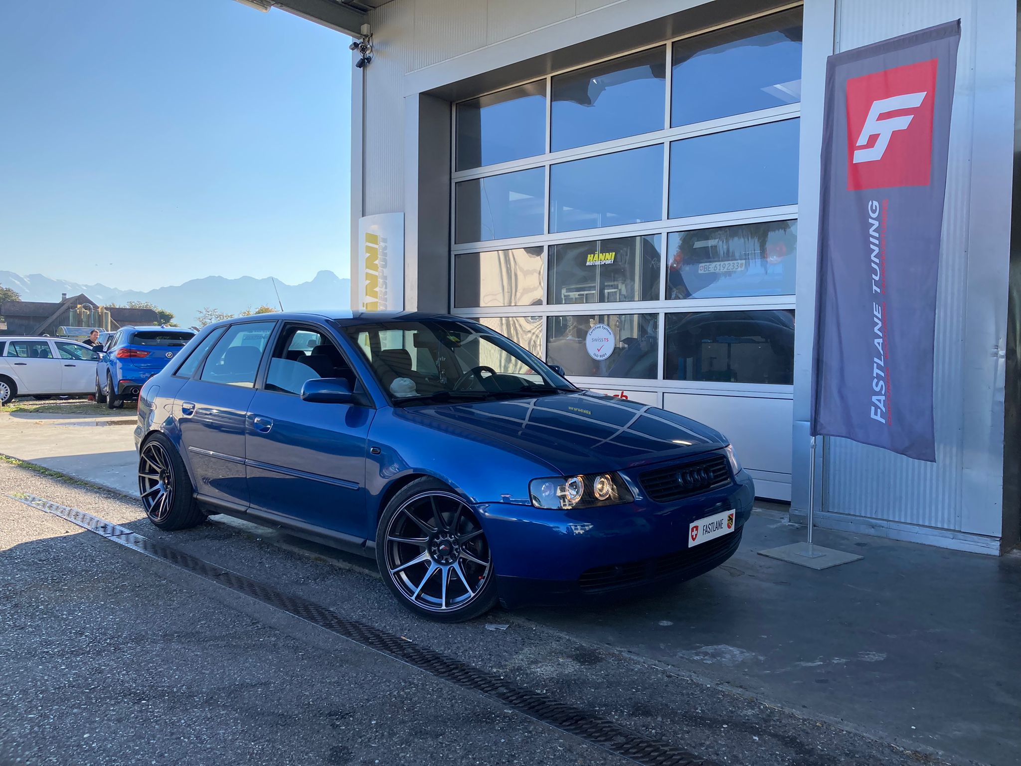 Ein blauer Audi A3 1.8 Turbo steht neben der fastlane tuning schweiz Flagge