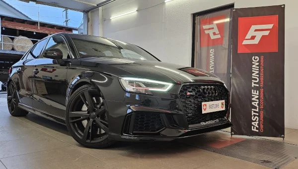 Eine schwarze RS3 Limousine steht neben dem Banner der Fastlane Tuning Schweiz GmbH