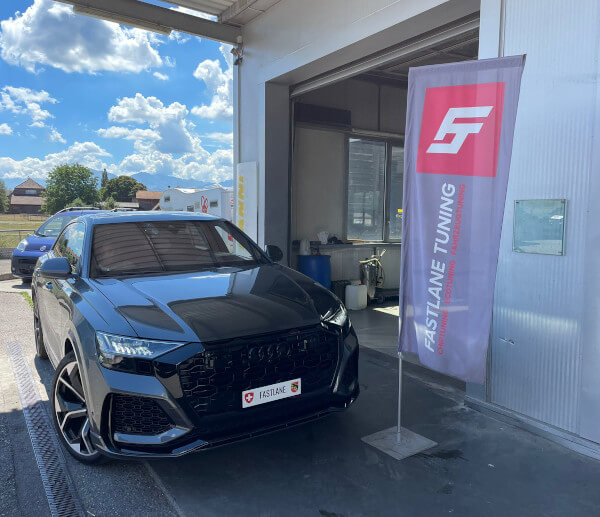 Ein grauer Audi RSQ8 steht neben der Fastlane Tuning Schweiz Flagge