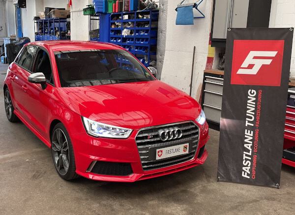 Ein roter Audi S1 steht neben dem Banner der Fastlane Tuning Schweiz GmbH