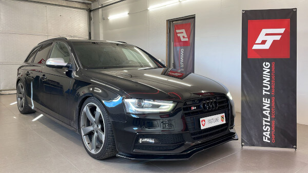 Ein schwarzer Audi S4 3.0 V6 Kompressor-Kombi steht neben dem Banner der Fastlane Tuning Schweiz GmbH