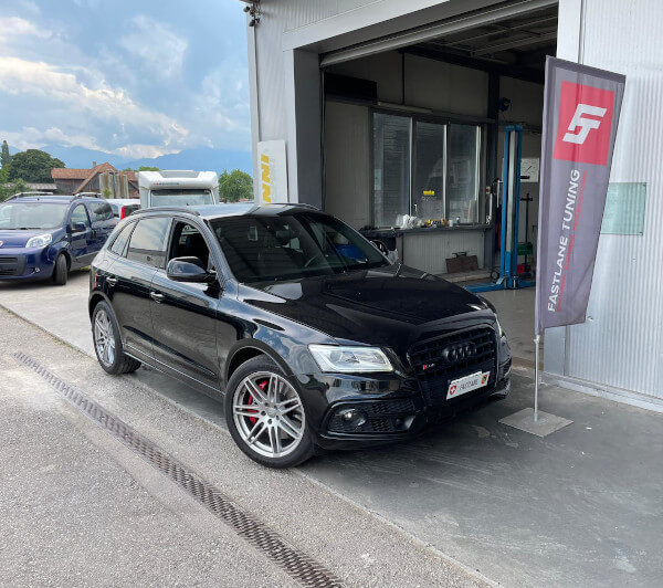 Ein schwarzer Audi SQ5 steht neben der Fastlane Tuning Schweiz Flagge.