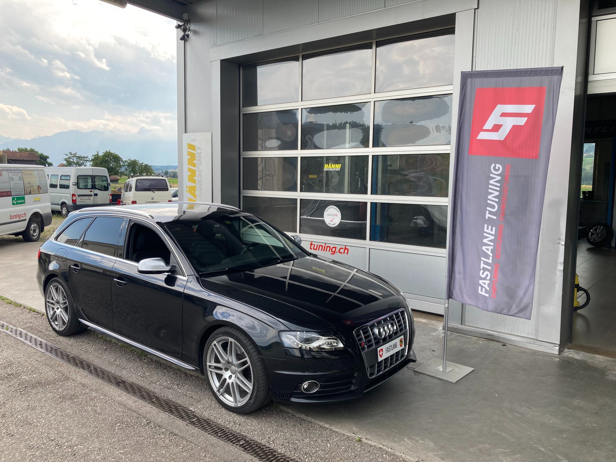 Ein schwarzer Audi A4 3.0 V6 TDI Kombi vor der Garage neben der Fastlane Tuning Schweiz Flagge