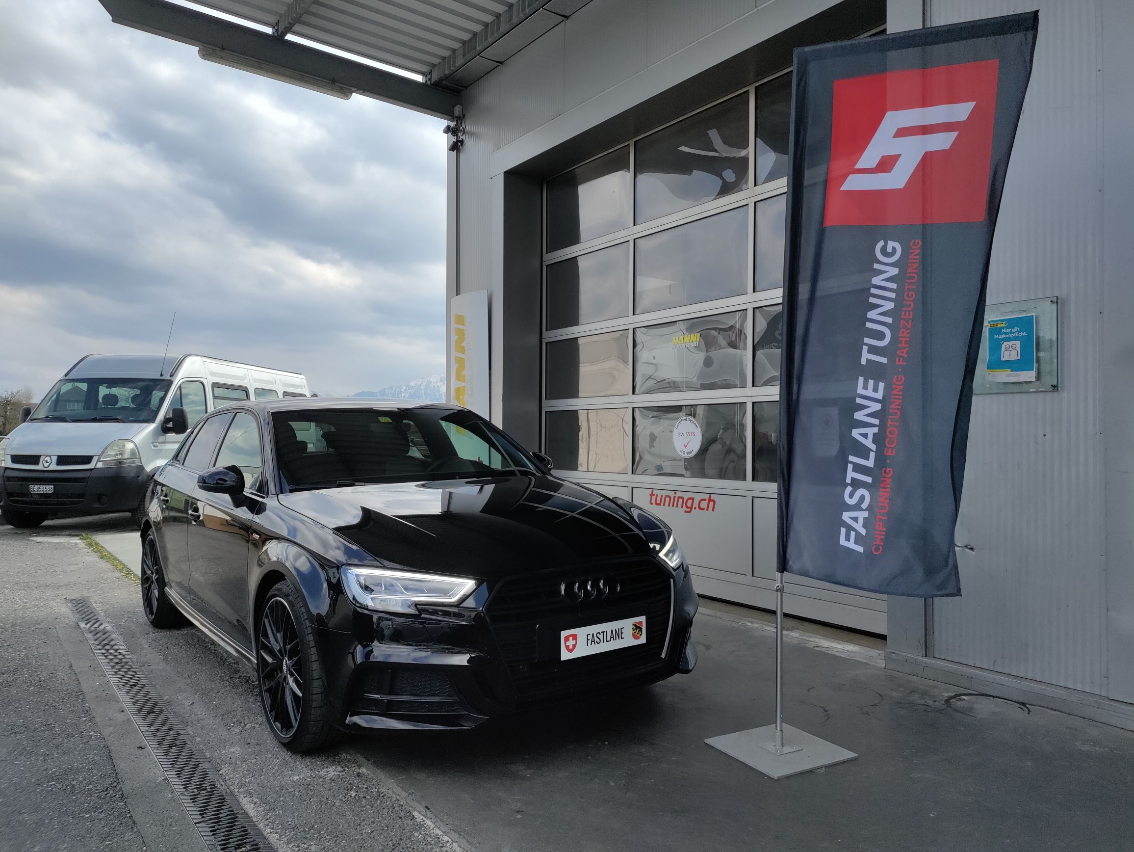 Eine schwarze A4 2.0 TDI Limousine steht neben der Fastlane Tuning Schweiz Flagge.