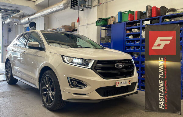 Ein weiss Ford Edge 2.0 TdCi biturbo steht neben das Fastlane Tuning Schweiz GmbH flagge