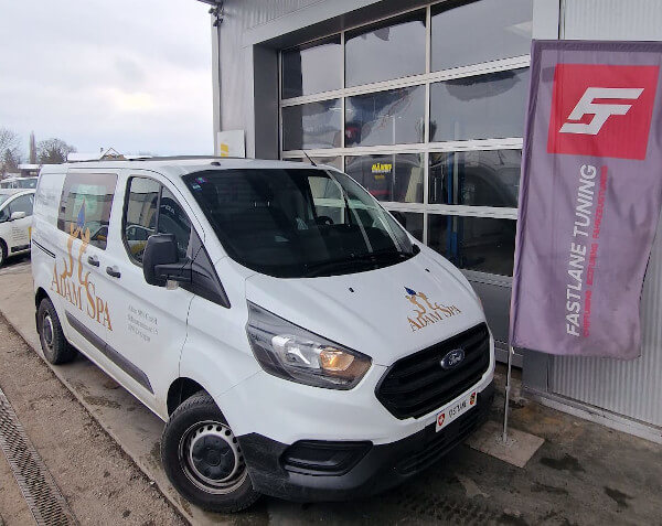 Ein weisser Ford Tourneo 2.0 TDCI steht neben der Fastlane Tuning Schweiz Flagge