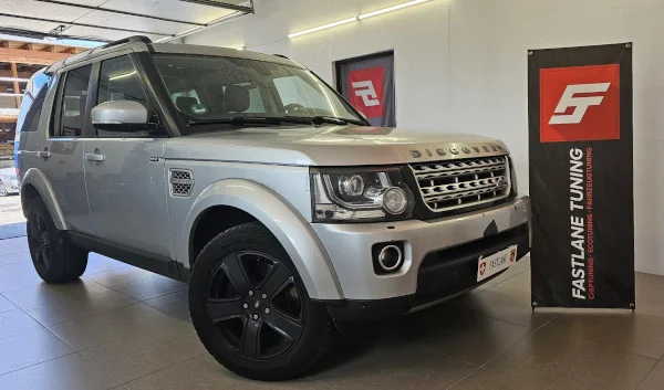 Neben dem Banner von Fastlane Tuning Schweiz steht ein grauer Landrover Discovery 4 SDV6