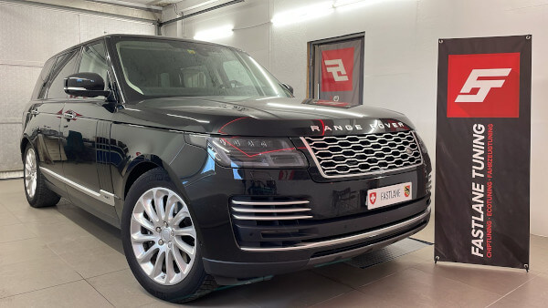 Ein schwarzer Range Rover V8 mit langem Radstand steht neben dem Banner der Fastlane Tuning Schweiz GmbH