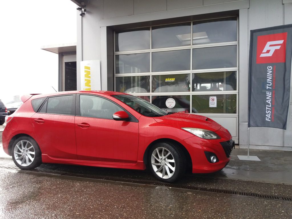 Ein knallroter Mazda 3 MPS steht vor der Garage neben der Fastlane Tuning Schweiz Flagge