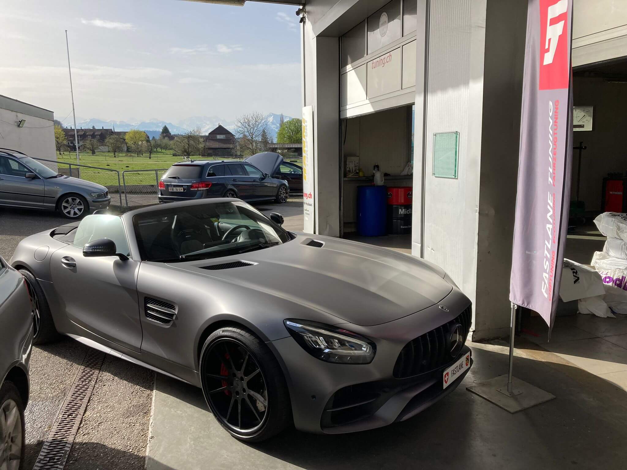 Ein mattgrauer GTC AMG steht neben der Fastlane Tuning Schweiz Flagge.