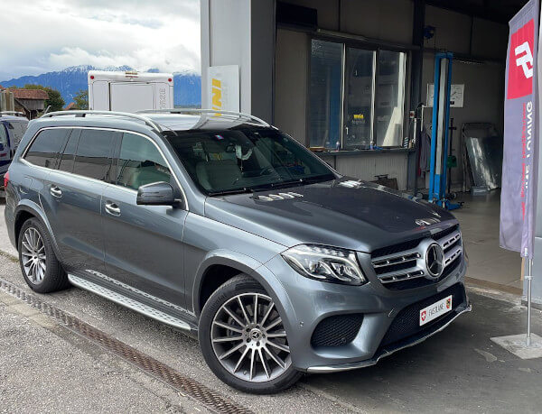 Ein grauer Mercedes GLS 350 CDI steht neben der Fastlane Tuning Schweiz Flagge.