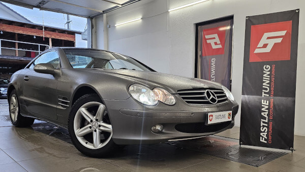 Neben dem Banner der Fastlane Tuning Schweiz GmbH steht ein grauer Mercedes Benz SL350