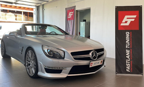 Ein silberner Mercedes Benz SL 500 steht neben dem Banner der Fastlane Tuning Schweiz GmbH.