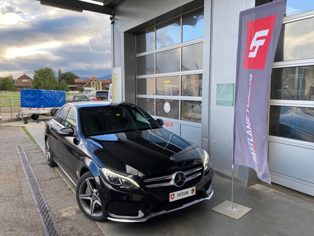 Ein schwarzer mercedes C400 steht neben der fastlane tuning schweiz Flagge