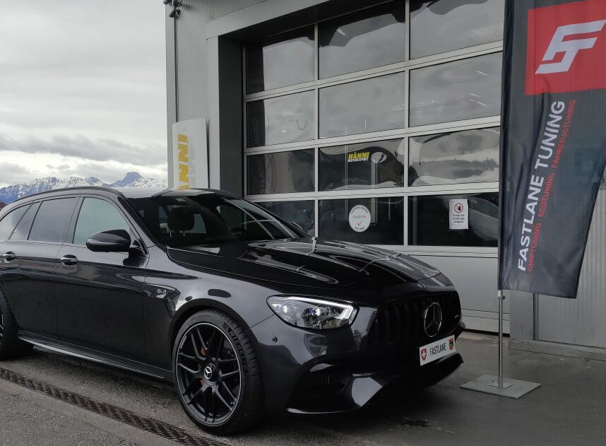 Ein Mercedes Benz E63 AMG S 2021 Facelift-Kombi steht vor der Garage neben der Fastlane Tuning Schweiz Flagge