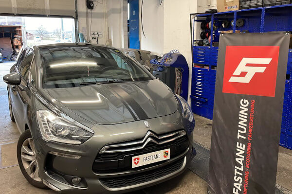 Ein grauer Citroen DS5 steht in der Garage von Fastlane Tuning Schweiz neben dem Fastlane-Banner