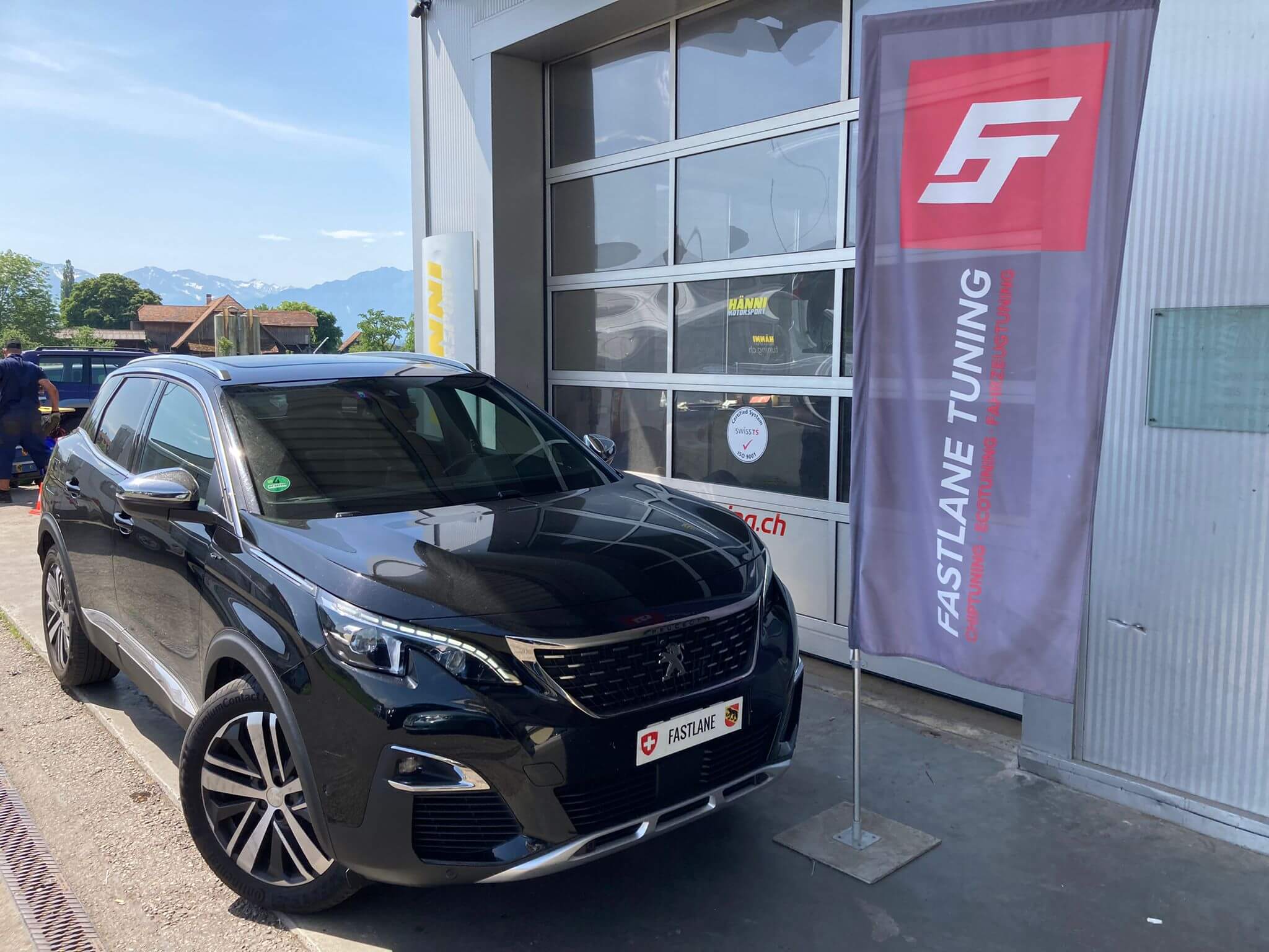 Ein schwarz Peugeot 3008 steht neben das Fastlane Tuning Schweiz Flagge