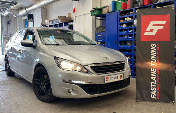 Ein silber Peugeot 308 HDI steht neben den Fastlane Tuning Schweiz GmbH flagge