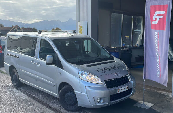 Ein grauer Peugeot Expert steht neben der Fastlane Tuning Schweiz Flagge