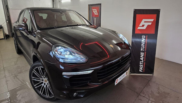 Neben dem Banner der Fastlane Tuning Schweiz GmbH steht ein schwarzer Porsche Cayenne Diesel S