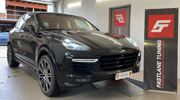 Ein schwarzer Porsche Cayenne Turbo S steht neben dem Banner der Fastlane Tuning Schweiz GmbH