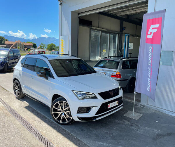 Ein weiss Ateca Cupra R mit stufe 1 softwareoptimierung und getriebeoptimierung steht neben das Fastlane Tuning Schweiz Flagge.