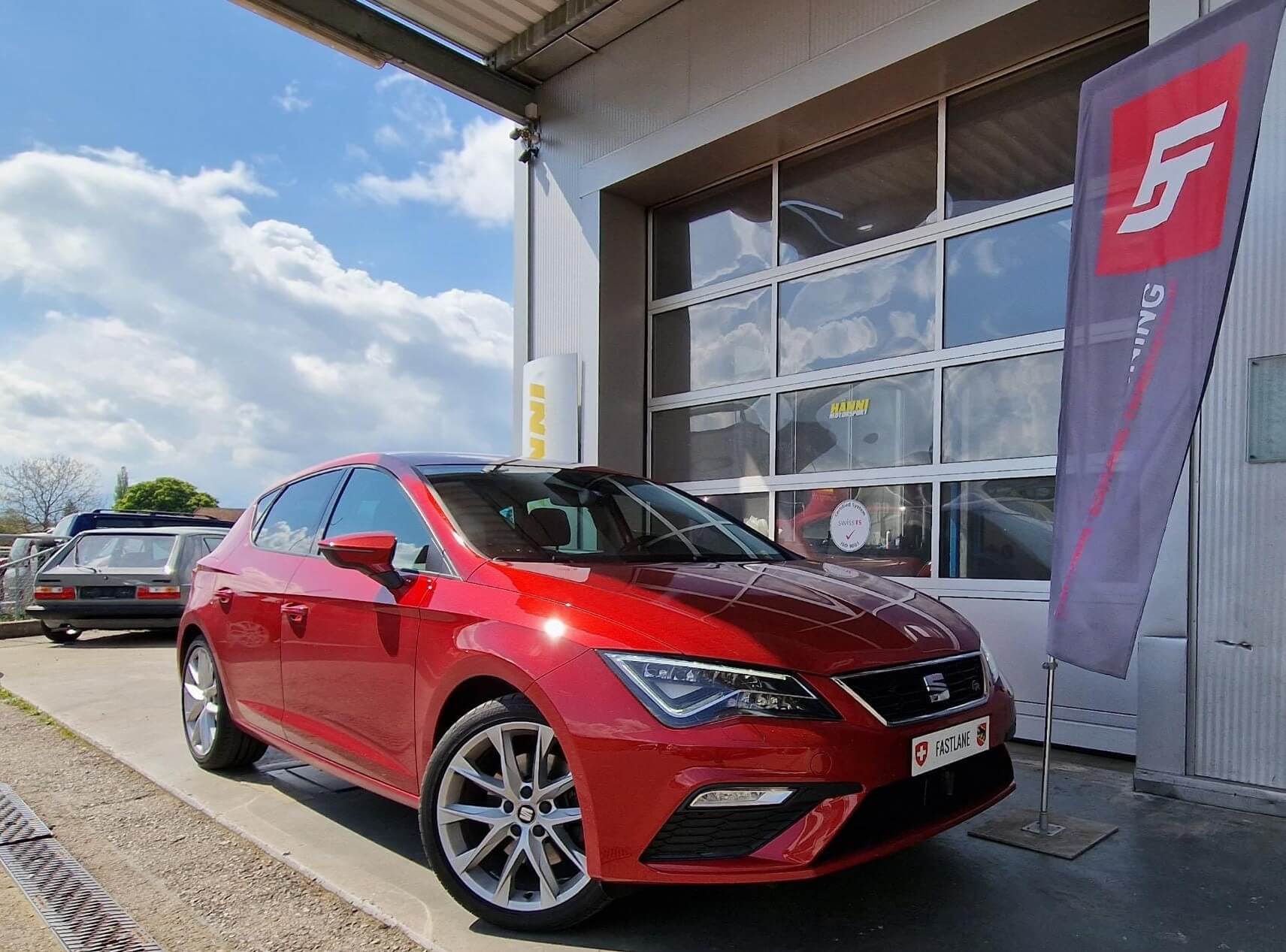 Ein roter SEAT Leon FR steht neben der Fastlane Tuning Schweiz Flagge