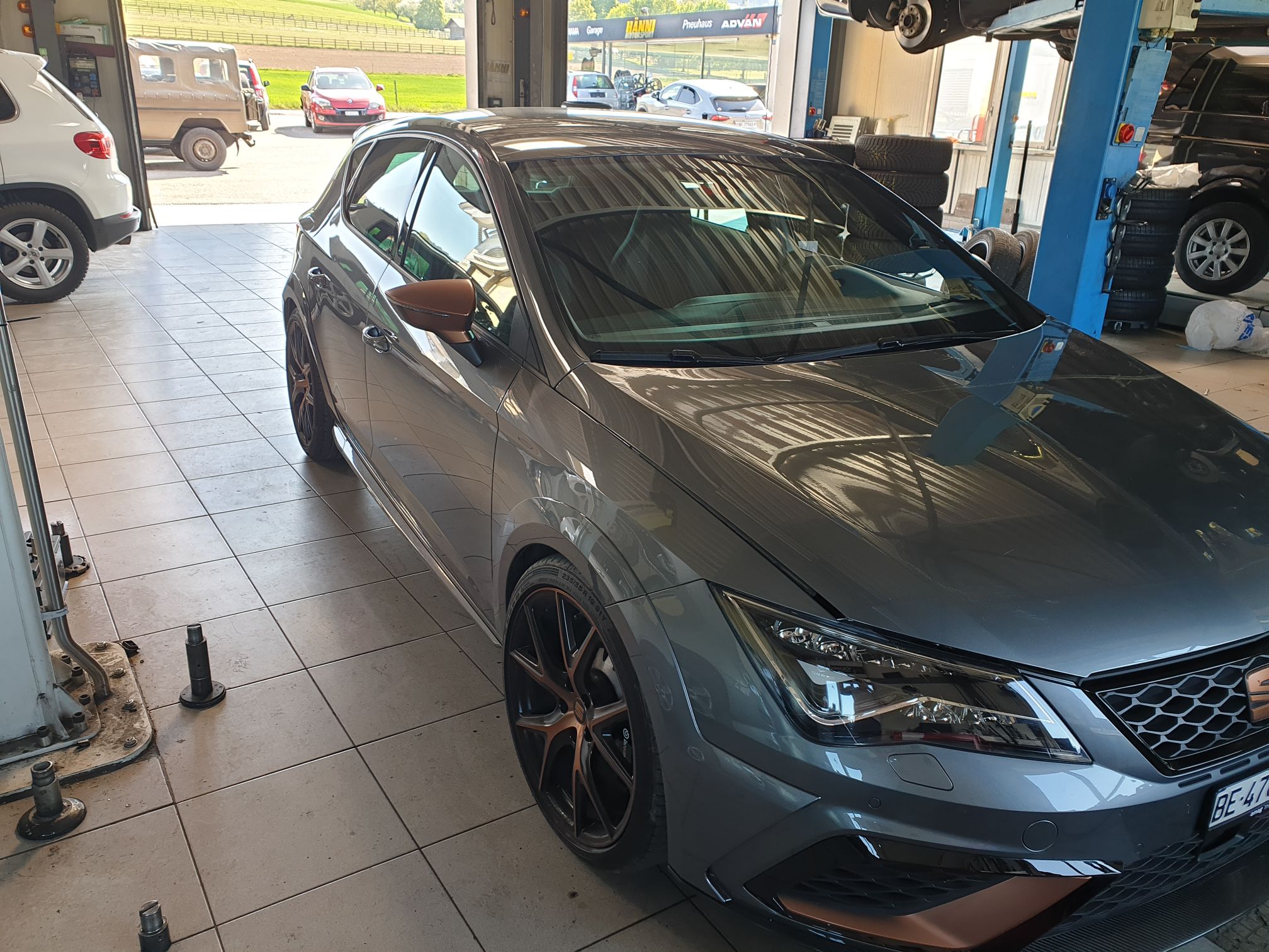 Ein dunkelgrauer SEAT Leon Cupra R mit braunen Einsätzen parkt in der Garage von Fastlane Tuning Schweiz