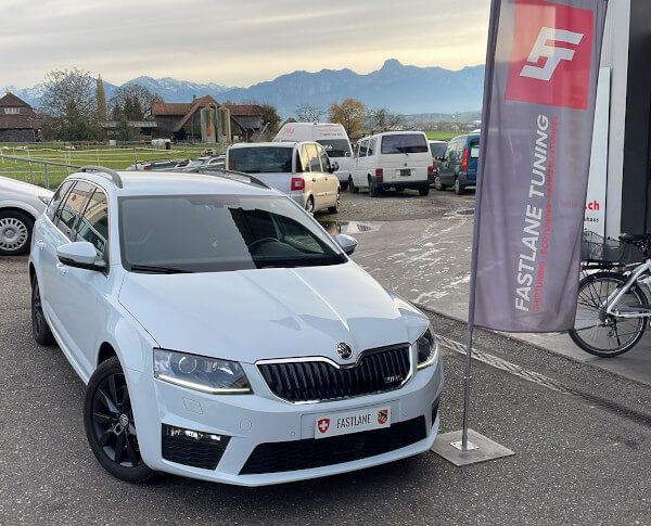 Ein weiss Skoda Octavia TSI RS steht neben das Fastlane Tuning Schweiz flagge