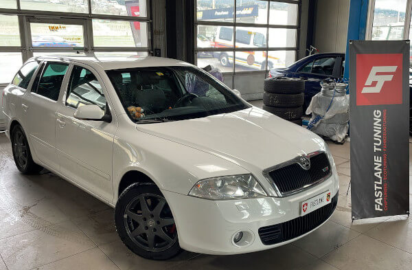 Ein weisser Skoda Octavia Kombi steht neben dem Banner von Fastlane Tuning Schweiz