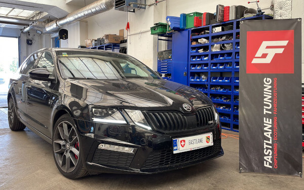 Eine schwarze Skoda Octavia VRS Limousine steht neben dem Banner der Fastlane Tuning Schweiz GmbH.