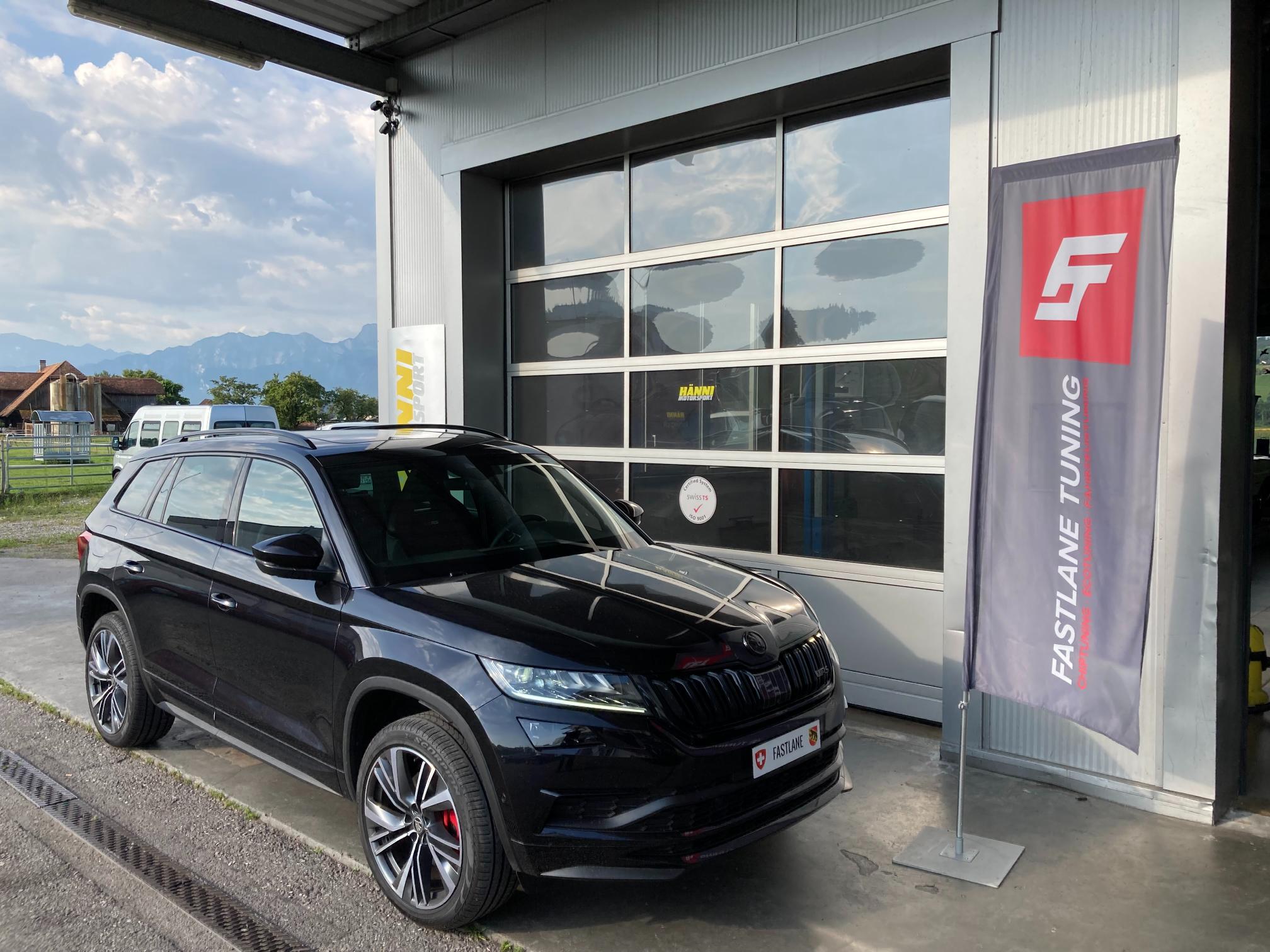 Ein schwarzer Skoda Kodiaq TDI RS steht vor der Garage neben der Fastlane Tuning Schweiz Flagge