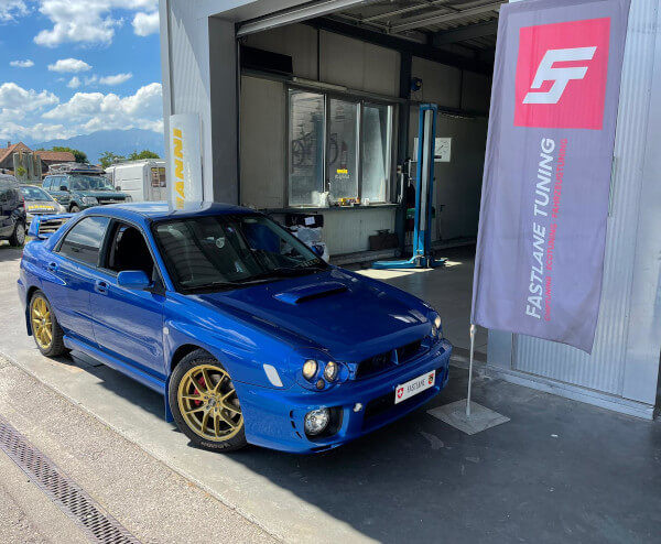 Ein blau Subaru Impreza WRX steht neban das Fastlane Tuning Schweiz Flagge