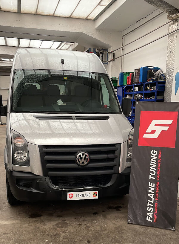 Ein silberner VW Crafter 2.5 L steht neben dem Fastlane Tuning Schweiz-Banner in der Garage