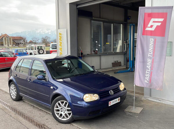 Ein blauer VW Golf Mk4 GTI steht neben der Fastlane Tuning Schweiz Flagge