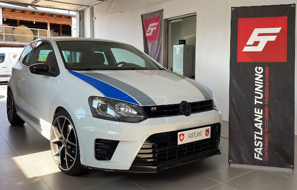 Ein weiss-blauer VW Polo GTI WRC Edition steht neben dem Banner der Fastlane Tuning Schweiz GmbH.