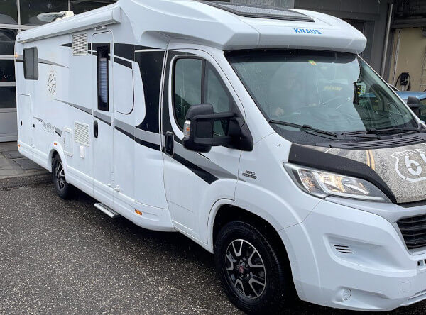 Ein majestätisches weißes Knaus-Wohnmobil auf Fiat-Basis steht vor der Garage von Fastlane. Es ist zu groß, um hineinzukommen.