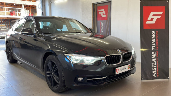 Eine schwarze BMW M340i Limousine steht neben dem Banner der Fastlane Tuning Schweiz GmbH