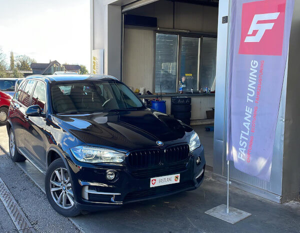 Ein Graues BMW X5 30d steht neben das Fastlane Tuning Schweiz flagge